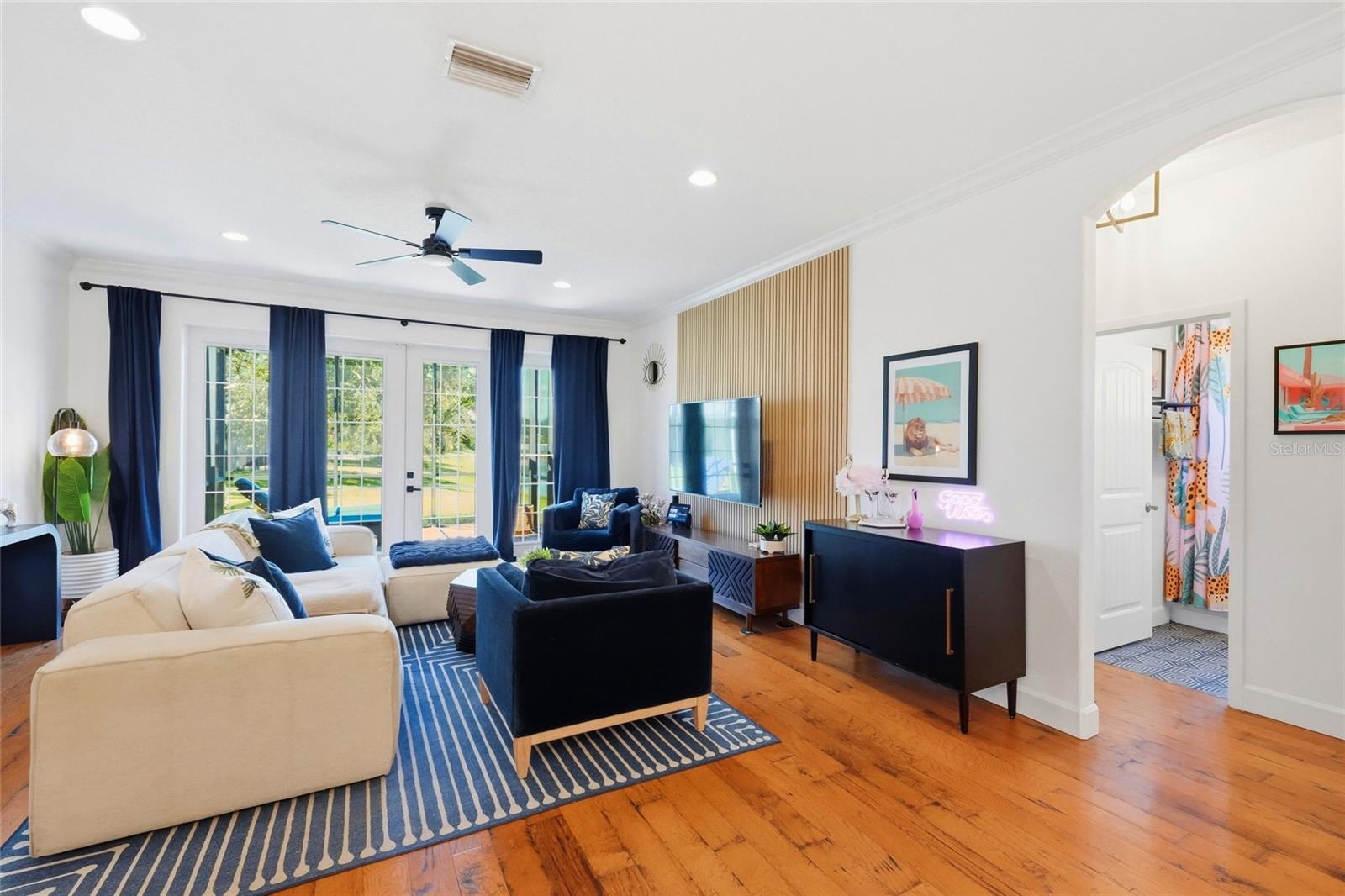 Living room with cream and navy seating, a striped rug, and glass doors overlooking a pool.