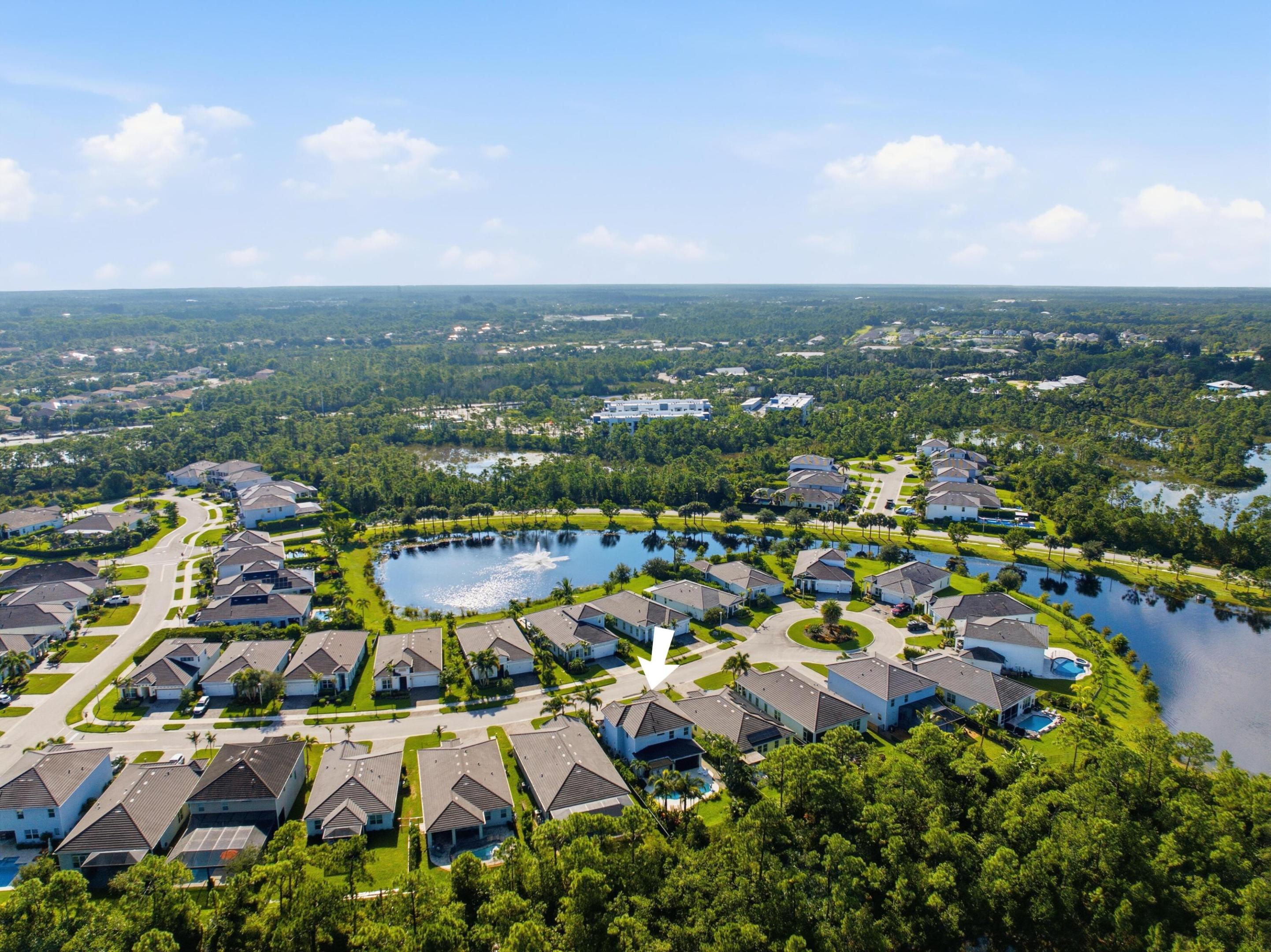 Aerial neighborhood view with an arrow marking a home beside a pond.