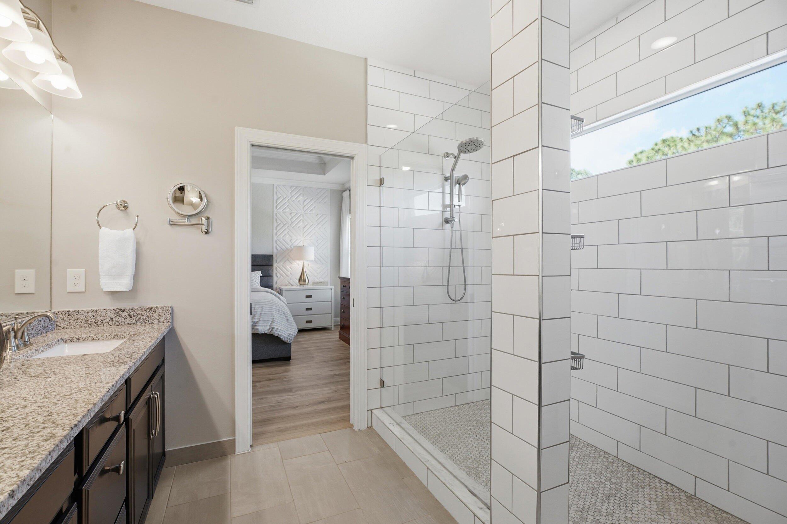 Bathroom with granite vanity and spacious white subway-tile walk-in shower.