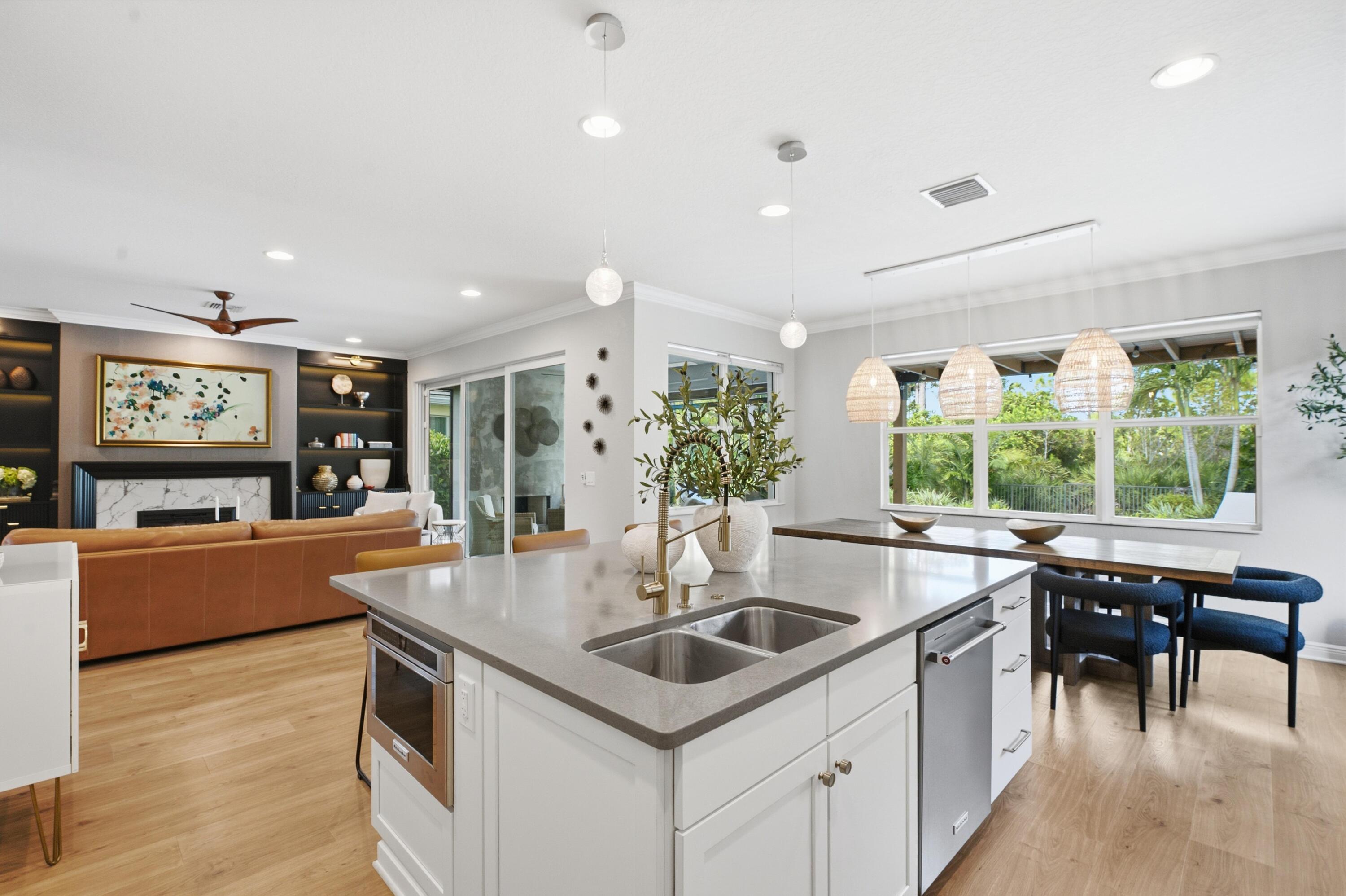 Open-plan kitchen with a large island and sink, dining area by wide garden-facing windows, and living room fireplace.