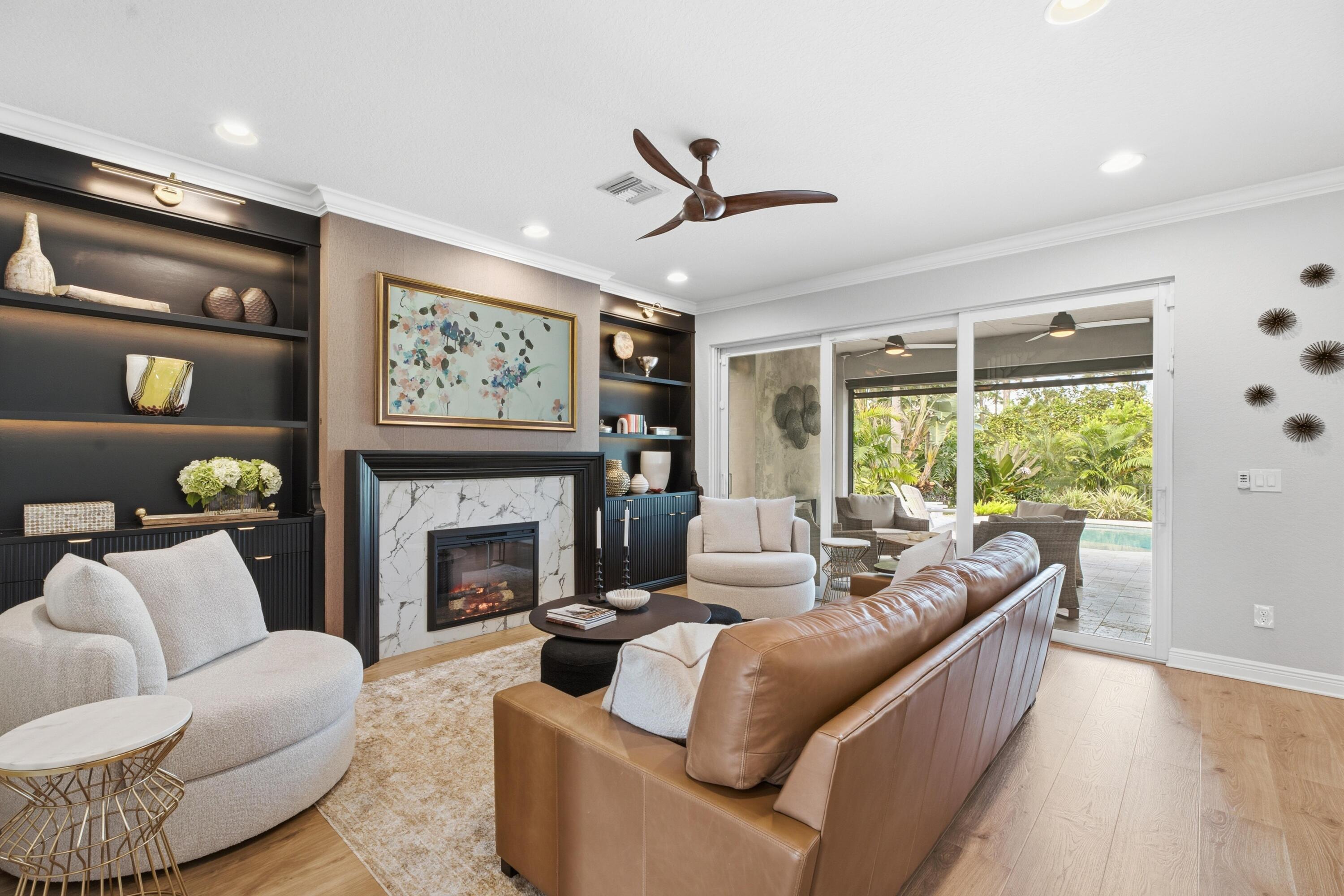 Living room with a marble fireplace, built-in shelving, leather sofa, and sliding doors to a patio.