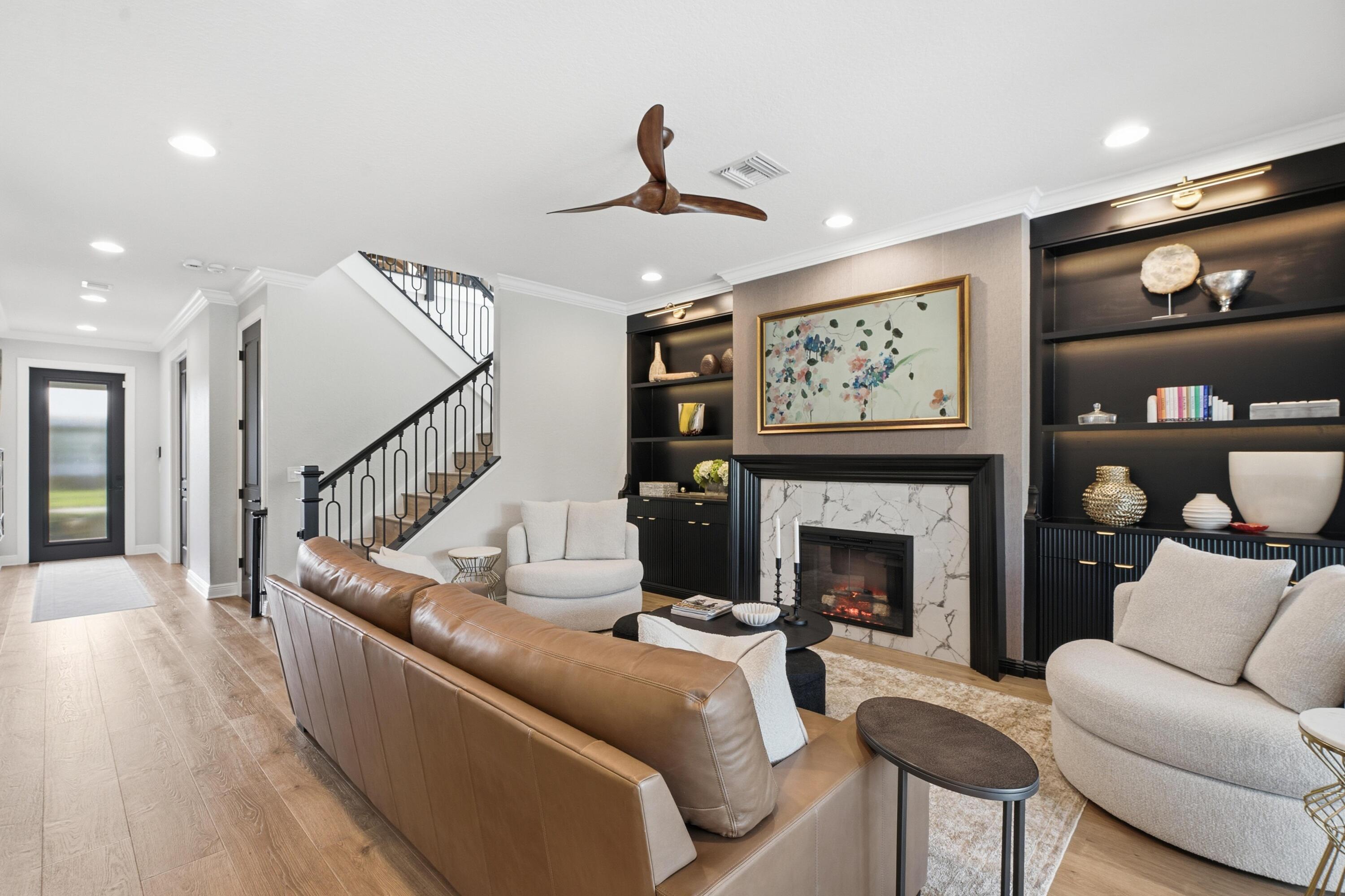 Living room with a marble fireplace, dark built-in shelves, and a staircase.