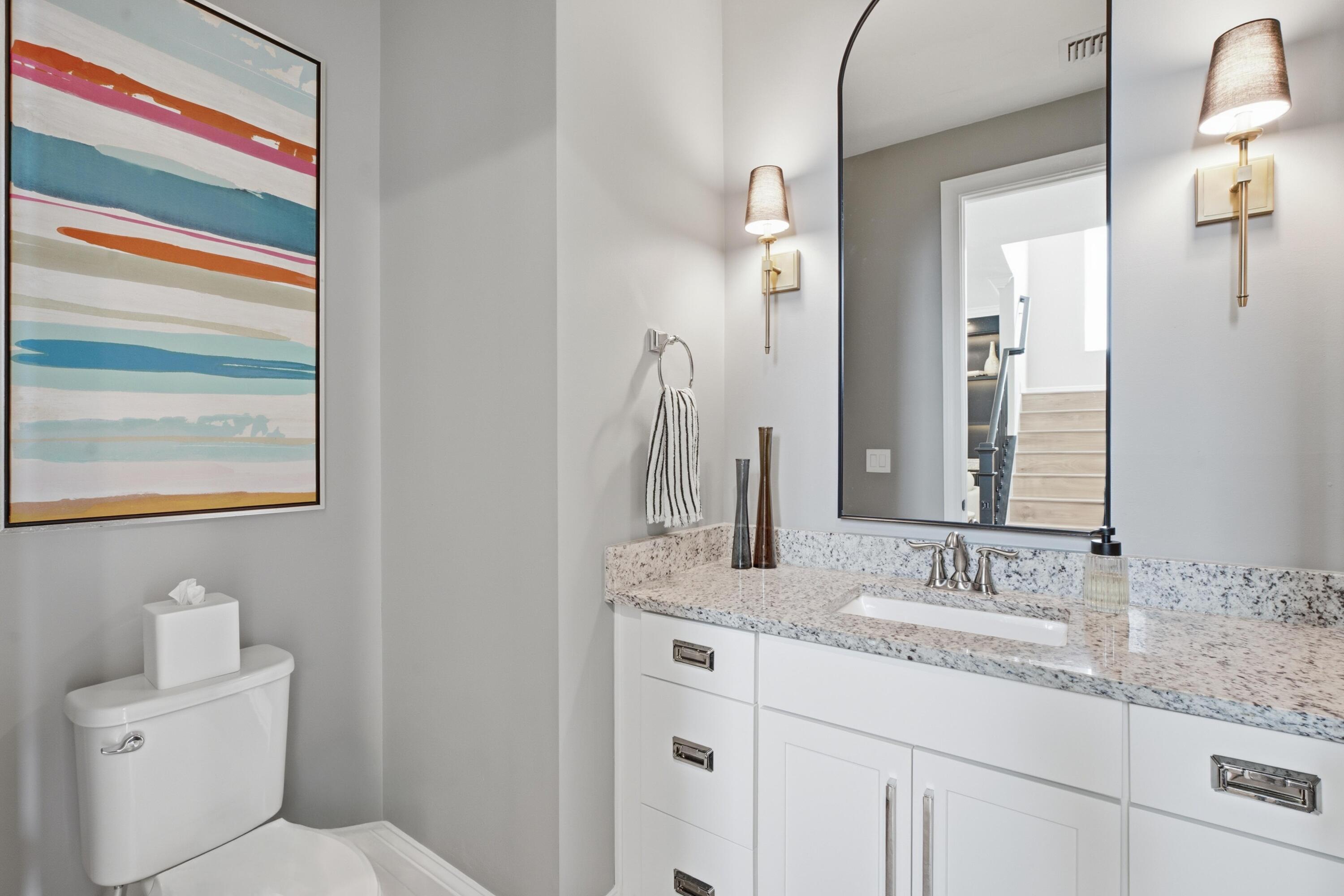 Bathroom with a white vanity and granite counter, large mirror, and colorful abstract wall art.