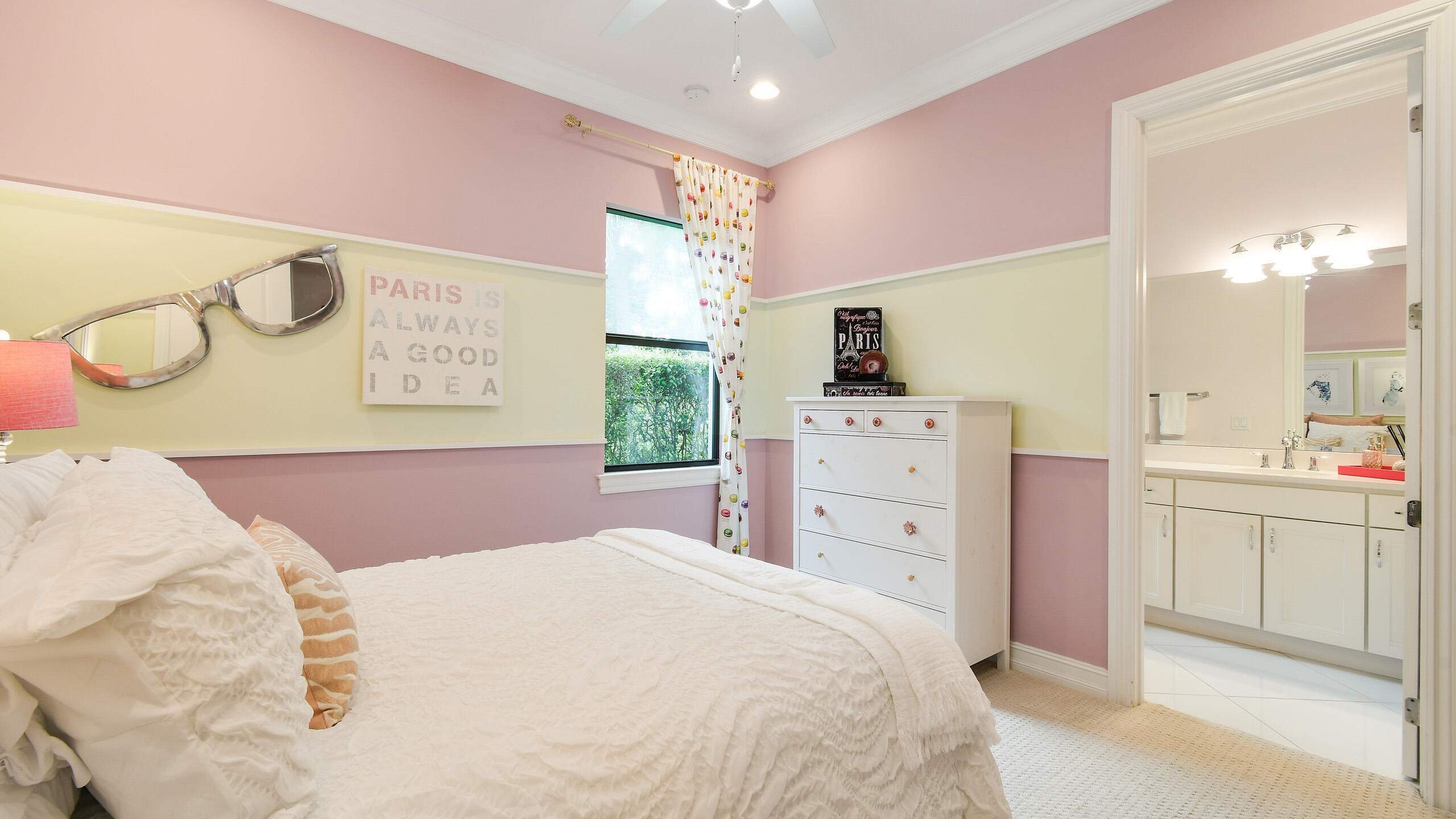 Bedroom with white bedding, pink and pale green walls, and a doorway to an ensuite bathroom.