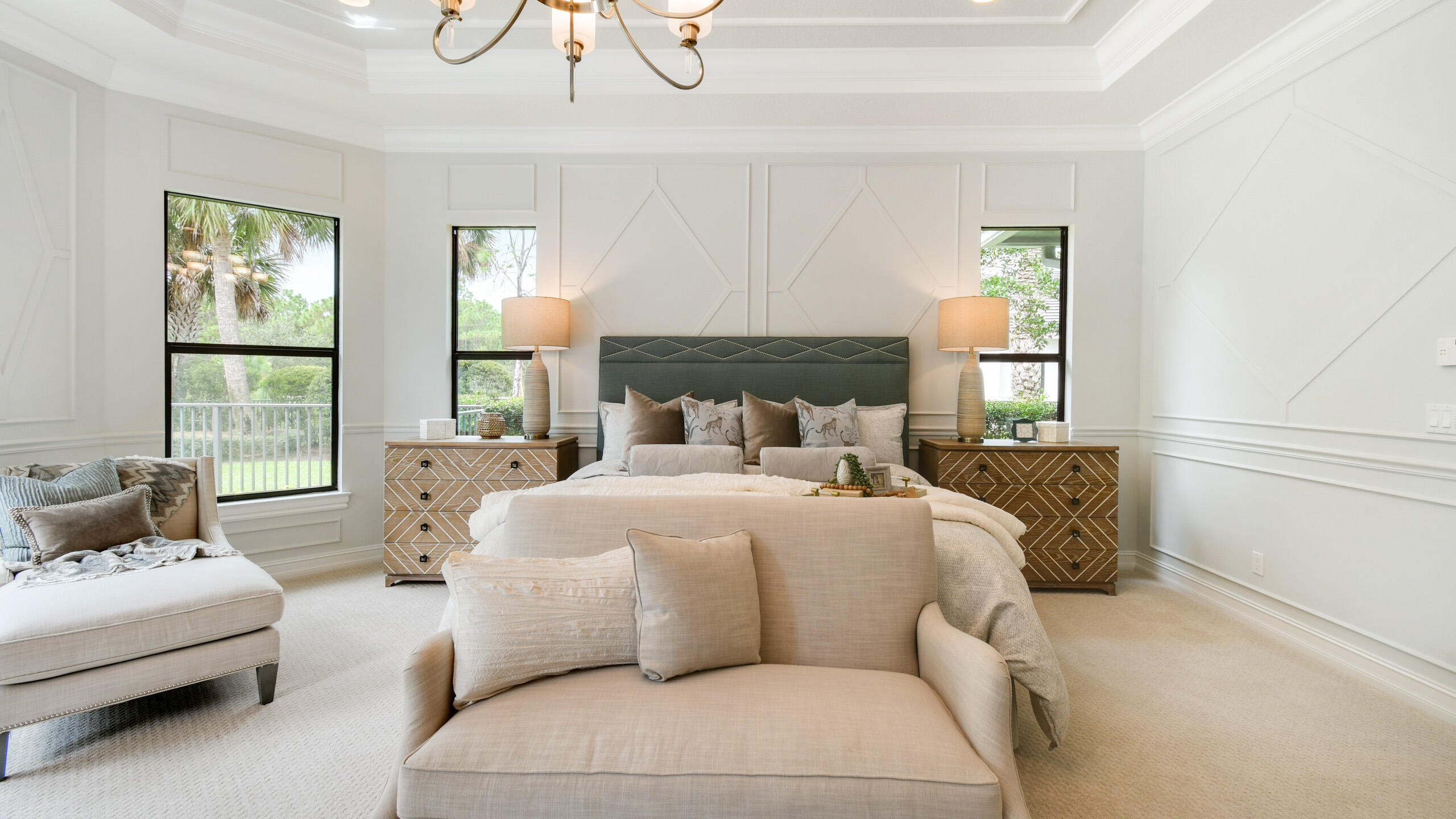Bright primary bedroom with a king bed, matching nightstands, and large windows overlooking greenery.