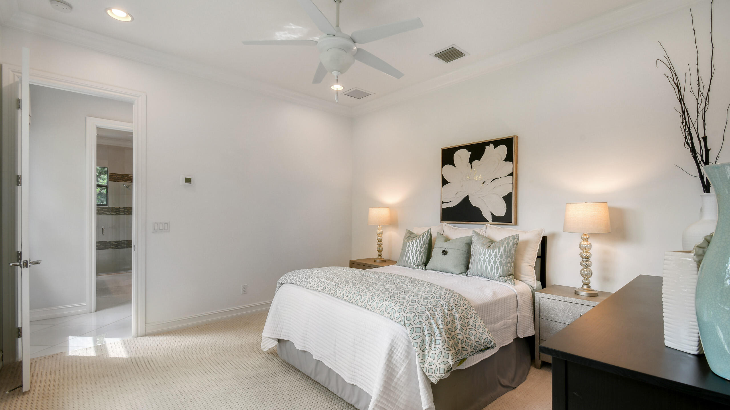 Staged bedroom with pale blue patterned bedding, matching lamps, and large floral wall art.