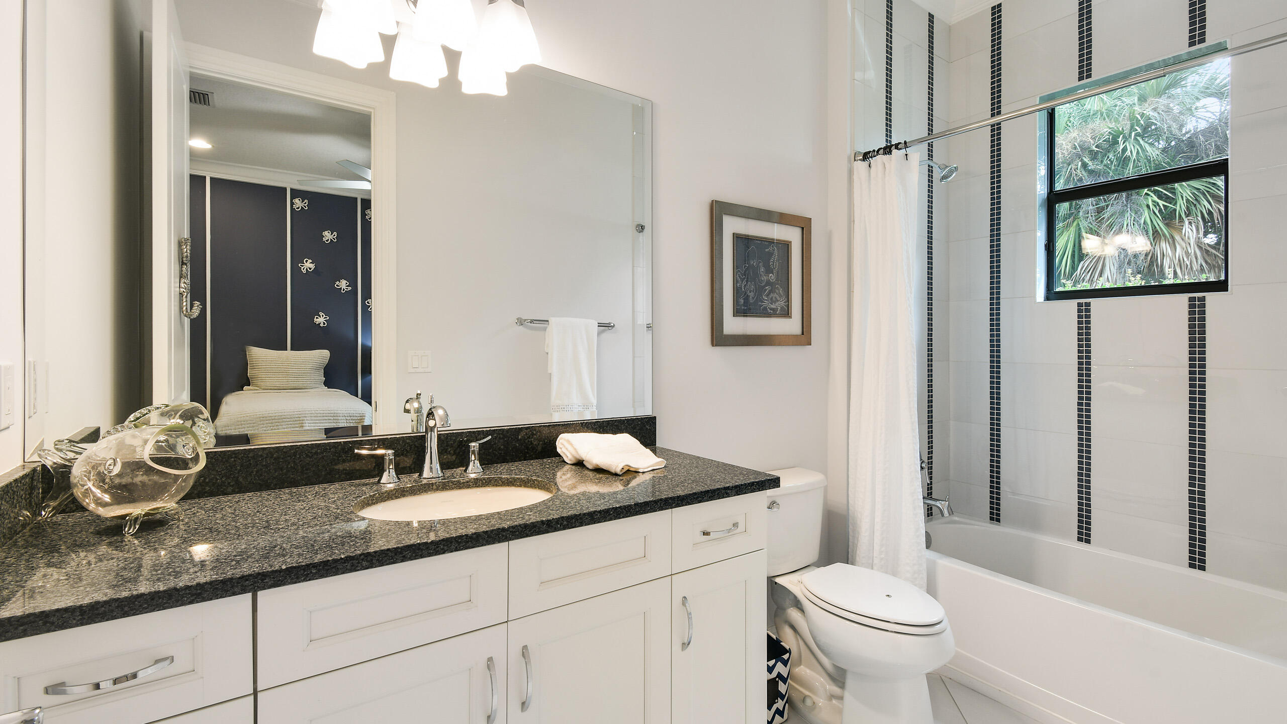 Bathroom with a black granite vanity, white cabinetry, and a tiled tub and shower.