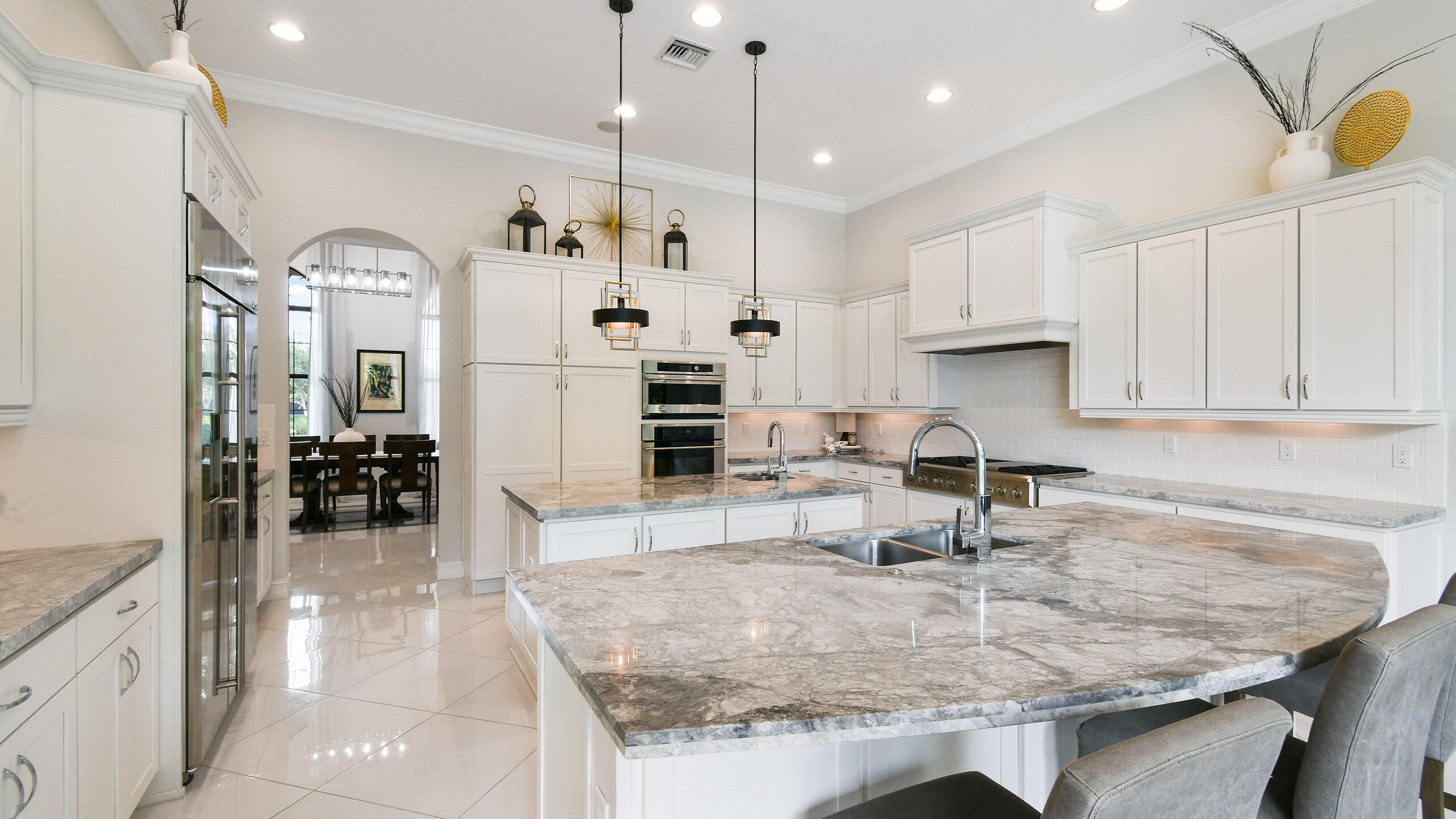 Kitchen with white cabinets, stainless steel appliances, and a large stone island with sink.