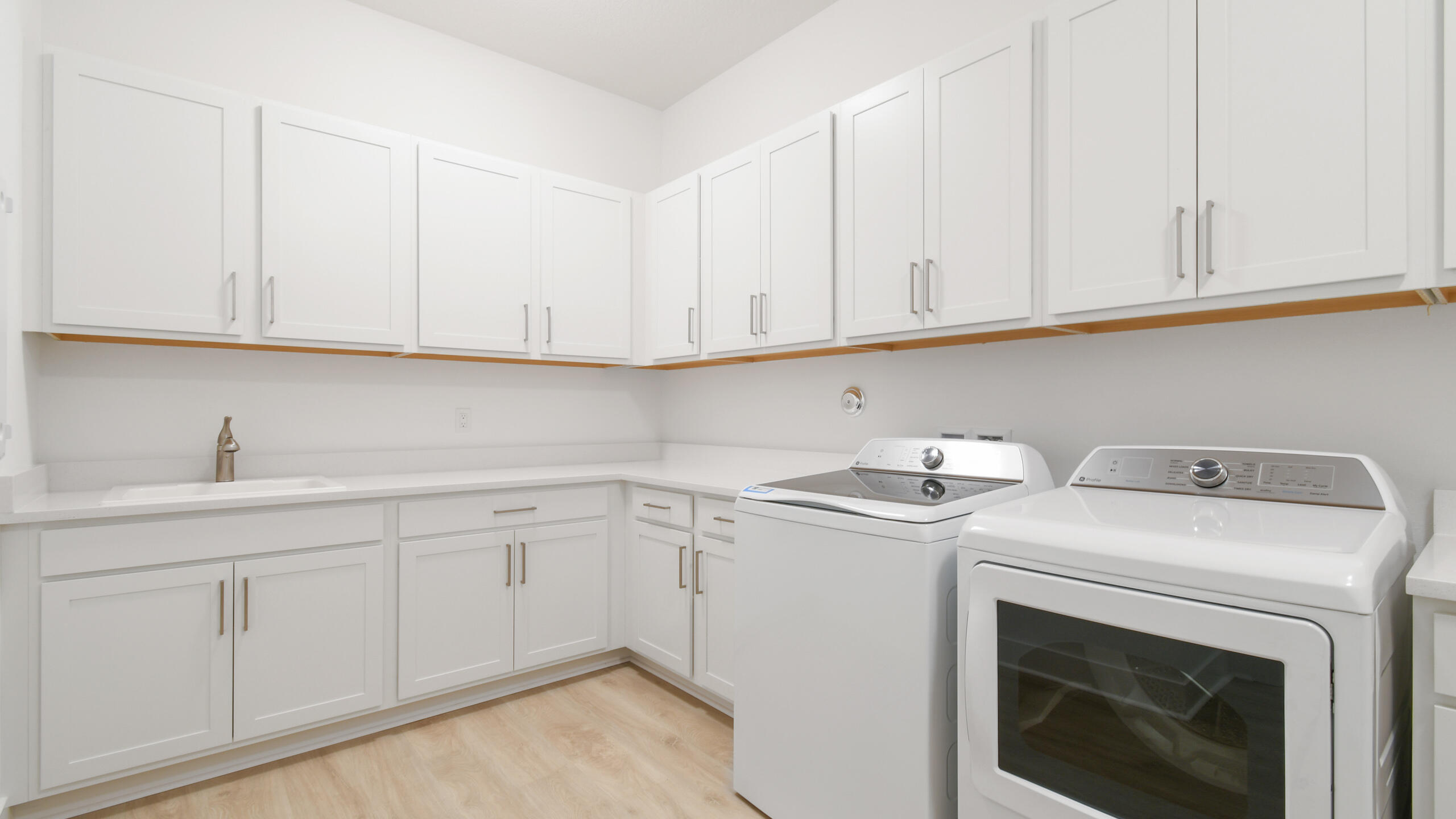 Laundry room with white cabinetry, a utility sink, and washer and dryer.