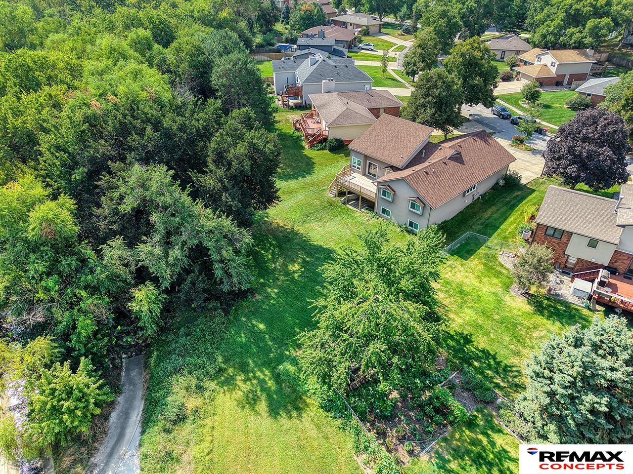 Aerial view of a home beside a broad, tree-bordered backyard.