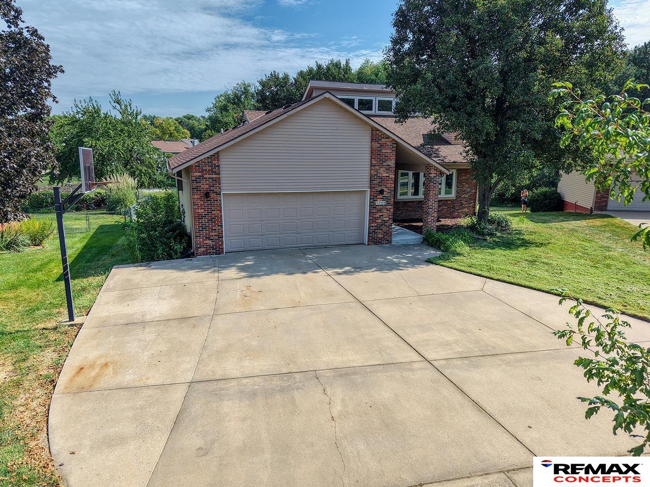 Brick-and-siding home with a two-car garage, broad driveway, and basketball hoop.