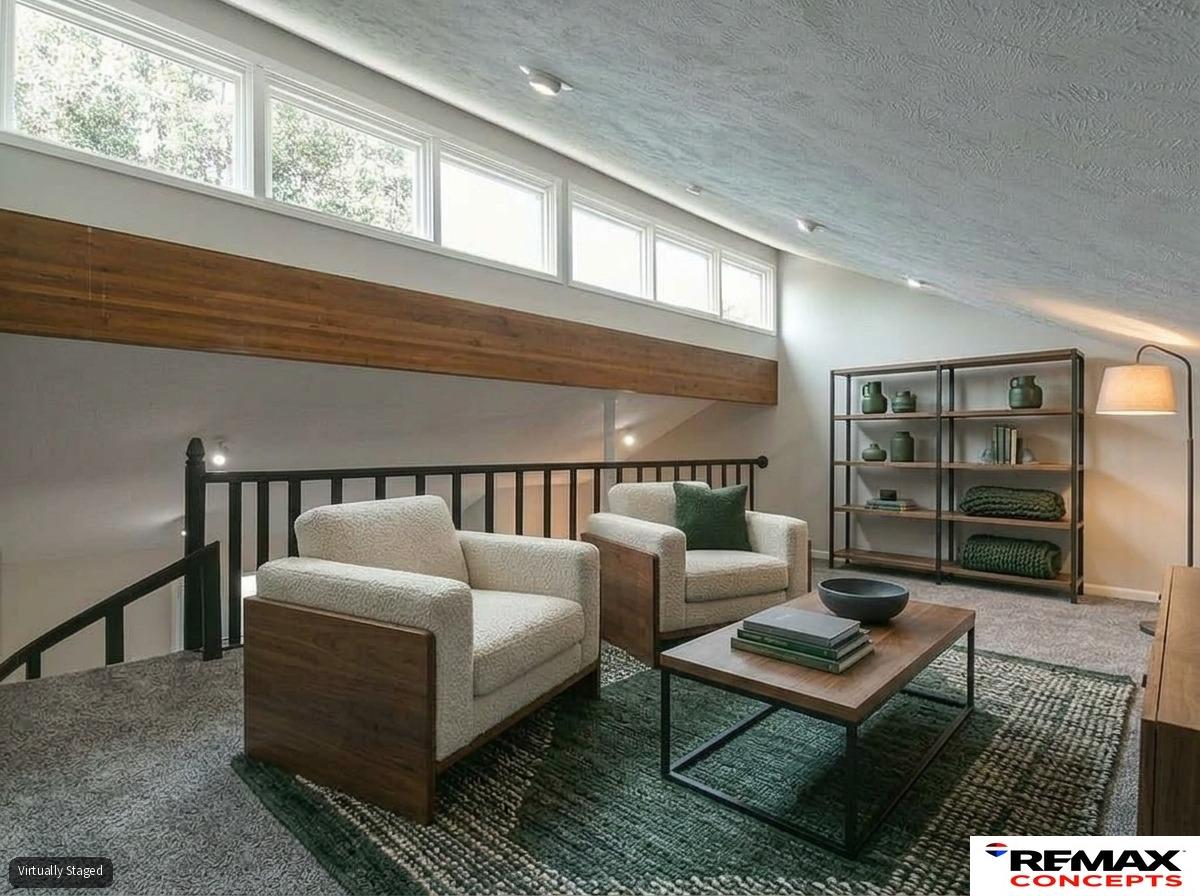 Loft sitting area with two armchairs, a coffee table, and high clerestory windows.