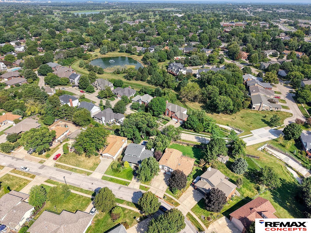 Aerial view of a tree-lined residential neighborhood with a pond and surrounding homes.