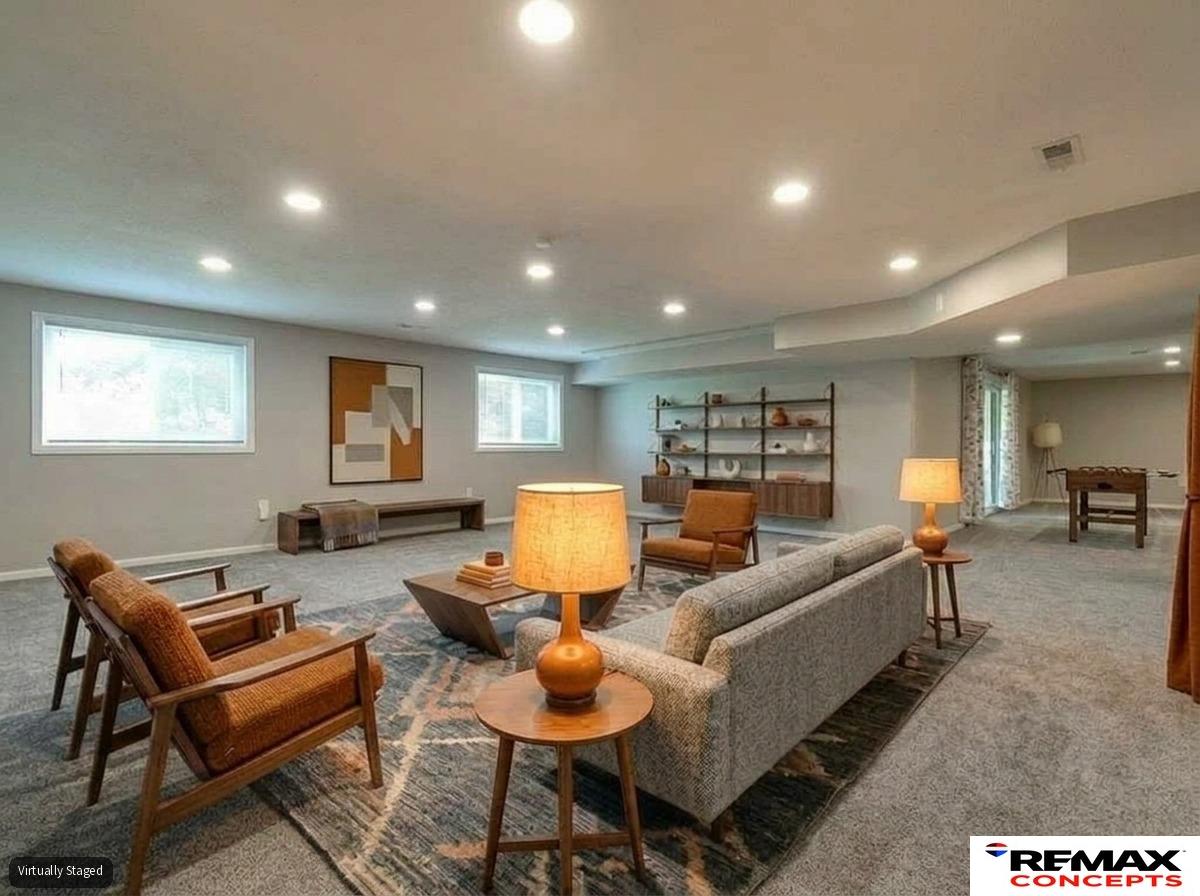 Virtually staged living room with a gray sofa, wooden armchairs, and an open dining area.