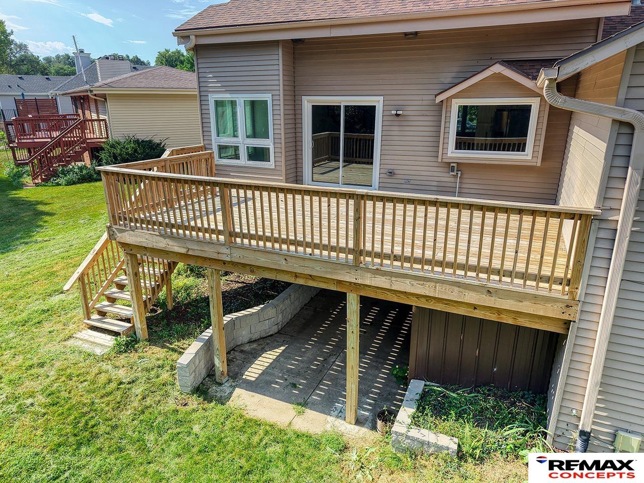 Rear of a house with a large elevated wooden deck and covered patio below.