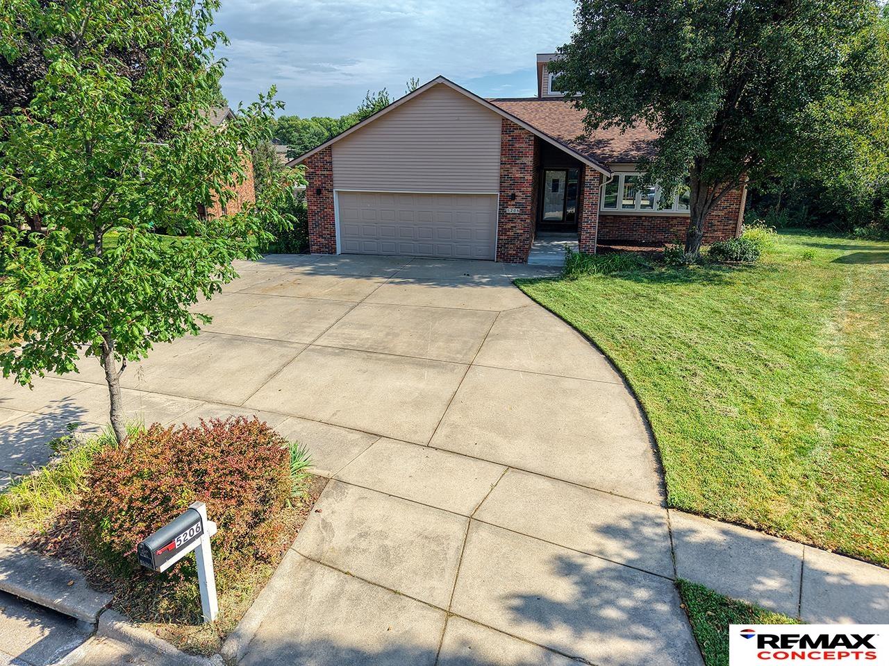 Brick-and-siding home with an attached garage, curved driveway, and landscaped front yard.
