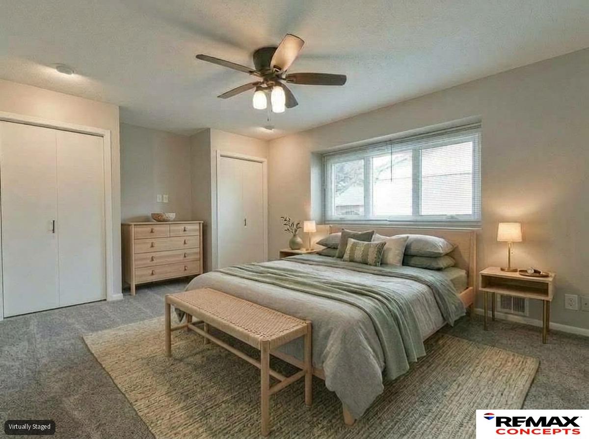 Bedroom with a staged bed, woven bench, dresser, and wide window with blinds.
