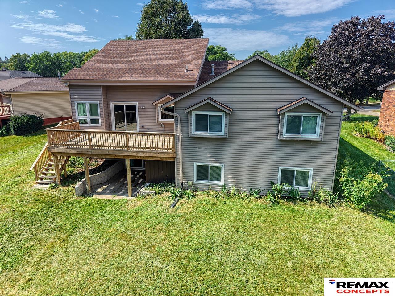 Rear exterior of a gray two-story home with a raised wooden deck and broad lawn.