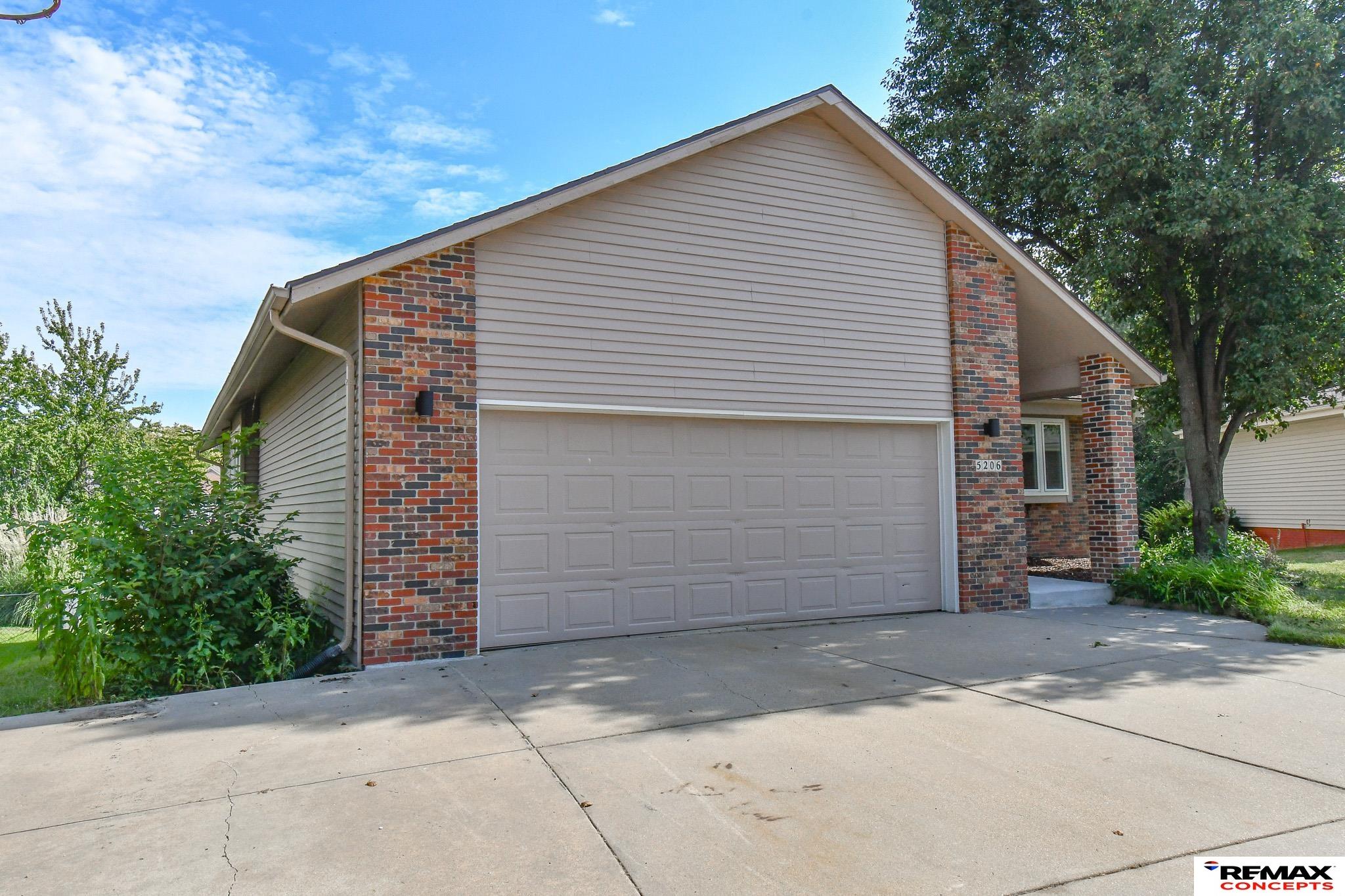 Home exterior with a large two-car garage, brick accents, and a broad concrete driveway.