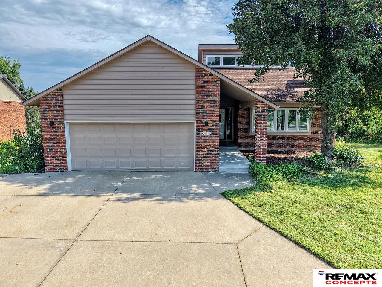 Front exterior of a brick-and-siding home with a wide double garage and covered entry.