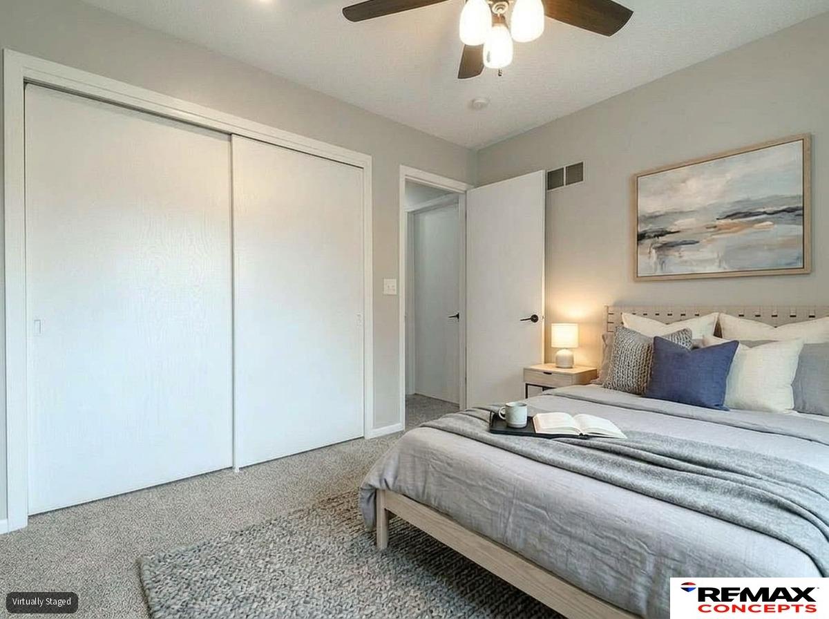 Staged bedroom with a gray bed, sliding closet doors, and ceiling fan.