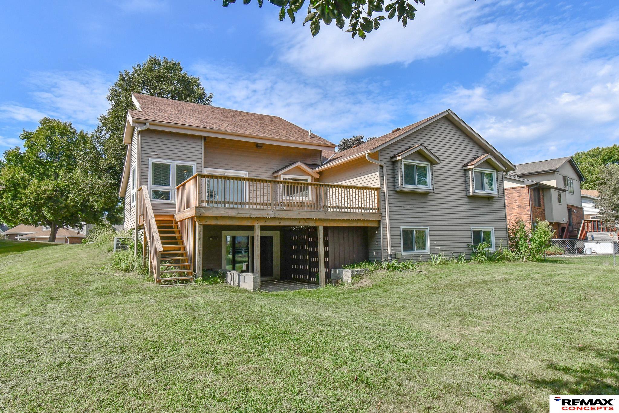 Rear of a gray two-story home with a raised deck, stairs, and walkout lower level.