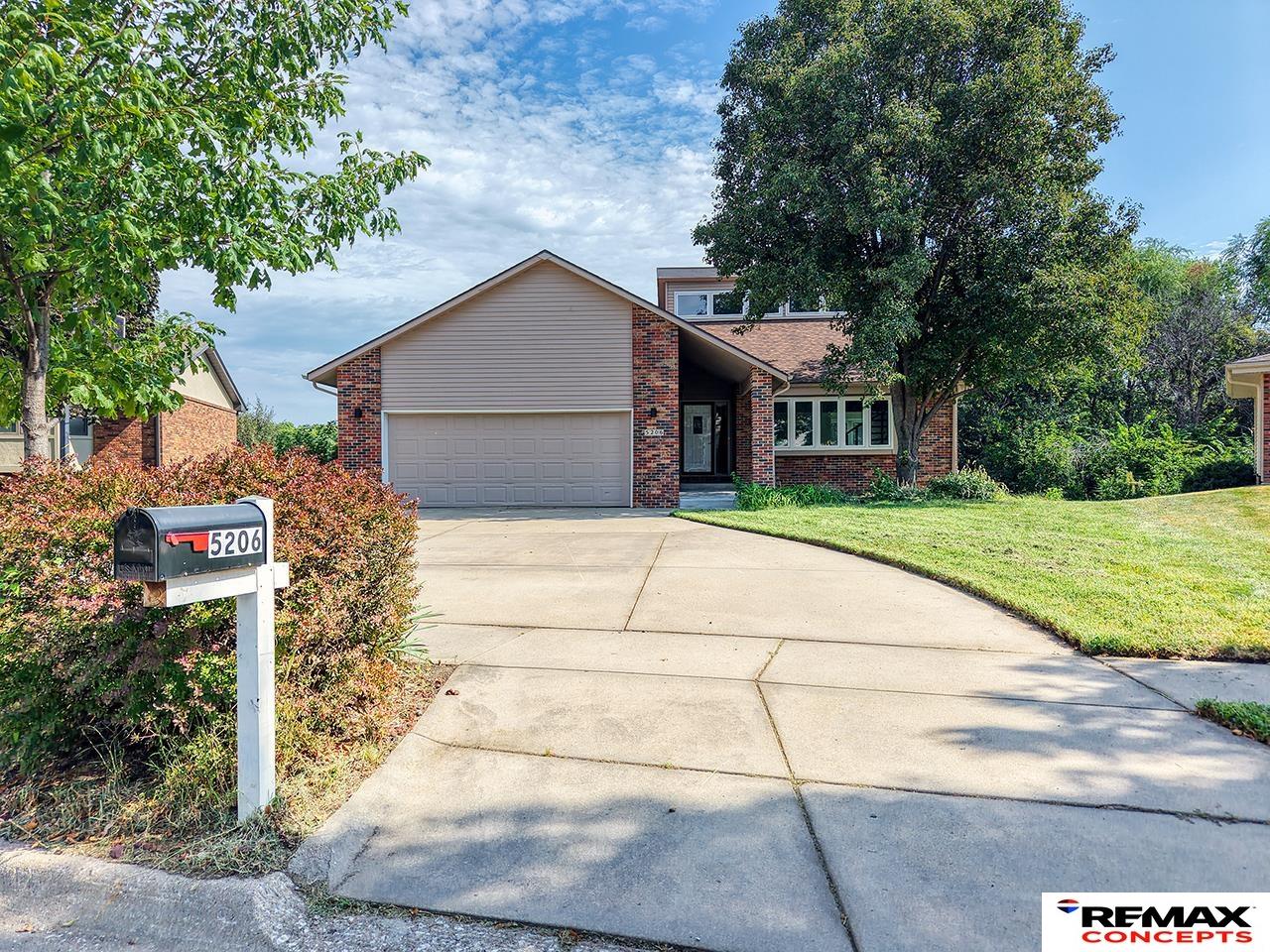 Two-story brick-and-siding house with a double garage, curved driveway, and mailbox marked 5206.
