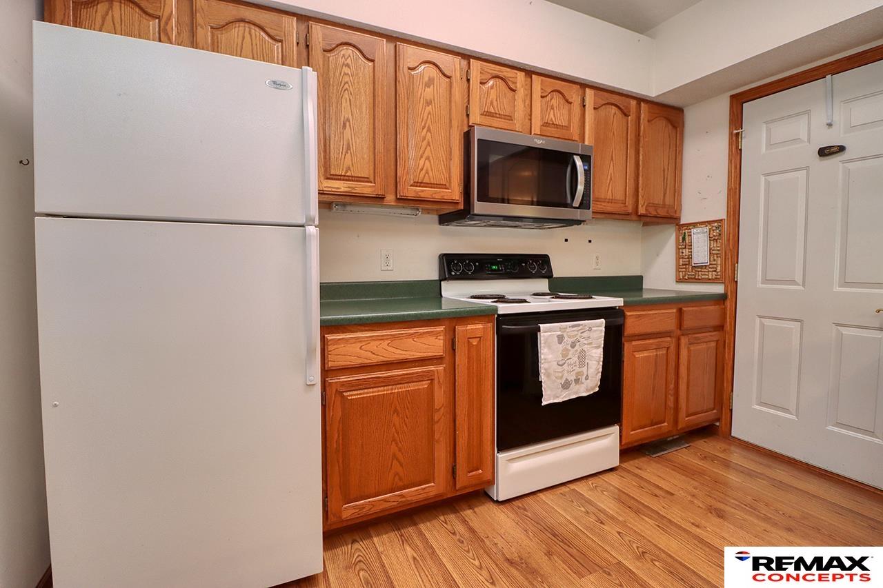 Kitchen with honey-colored cabinets, green countertops, and a white refrigerator beside the range.