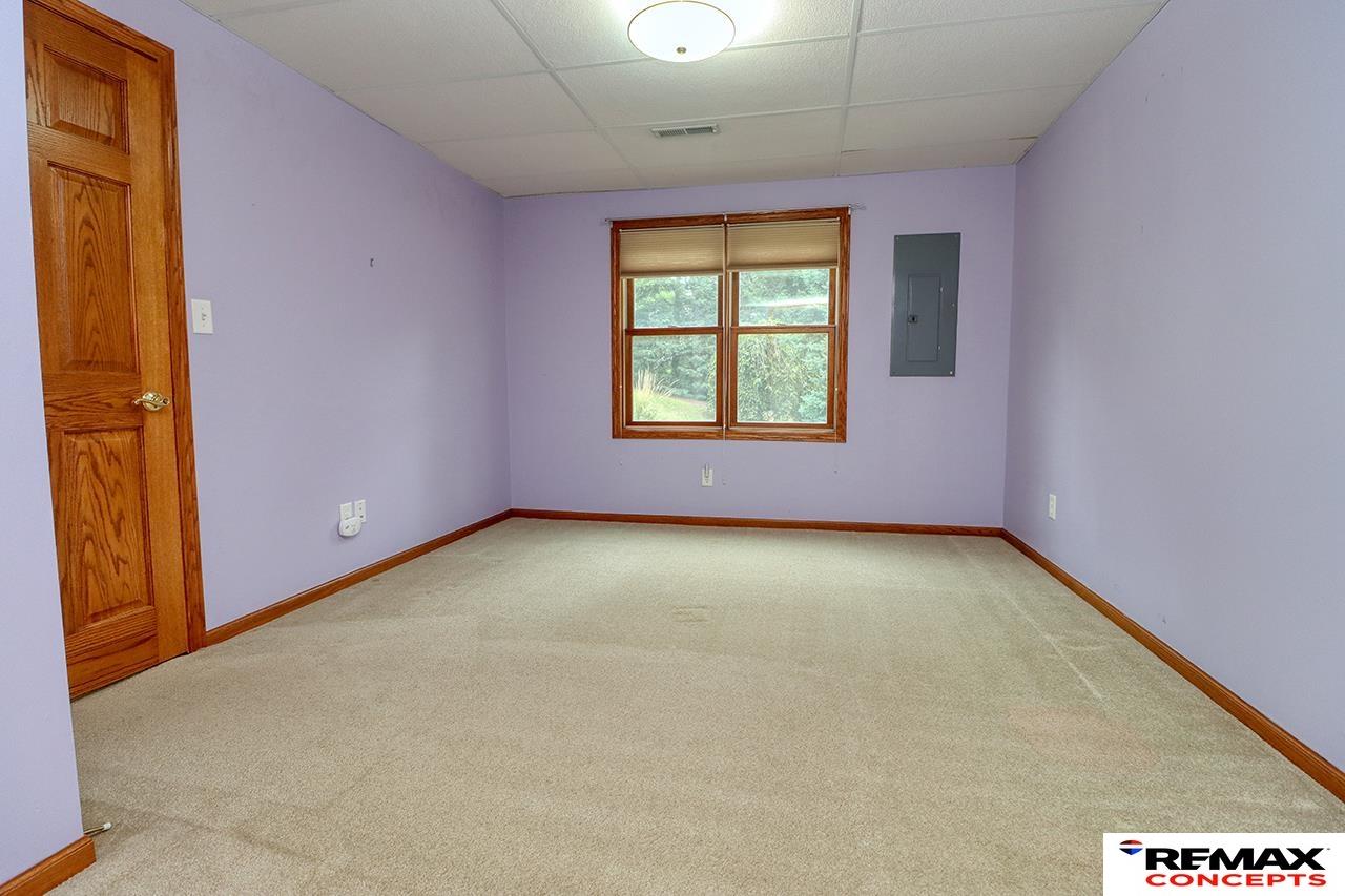 Empty room with lavender walls, beige carpet, and a wood-trimmed window.