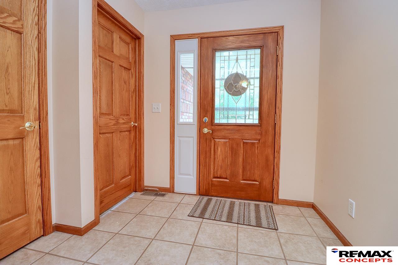 Entry foyer with tiled floor, oak interior doors, and a front door with decorative glass.