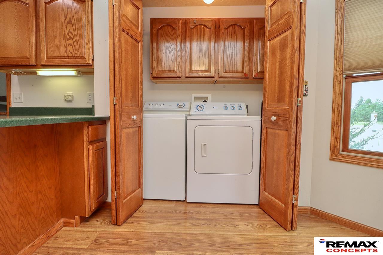 Laundry area with a washer and dryer behind open wood cabinet doors.