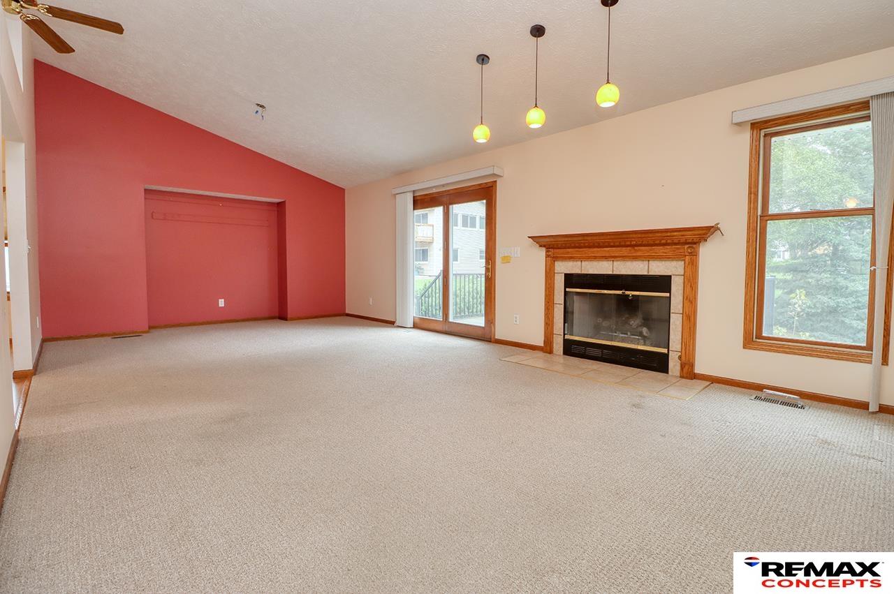 Vacant living room with a red accent wall, wood-trimmed fireplace, and sliding glass doors.