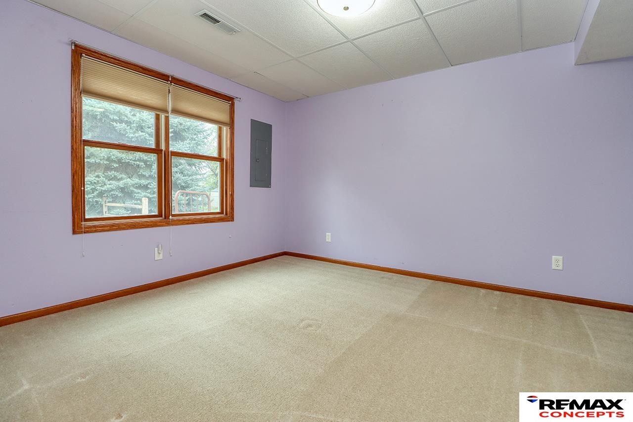 Empty carpeted room with lavender walls, wood trim, and a wide double window.