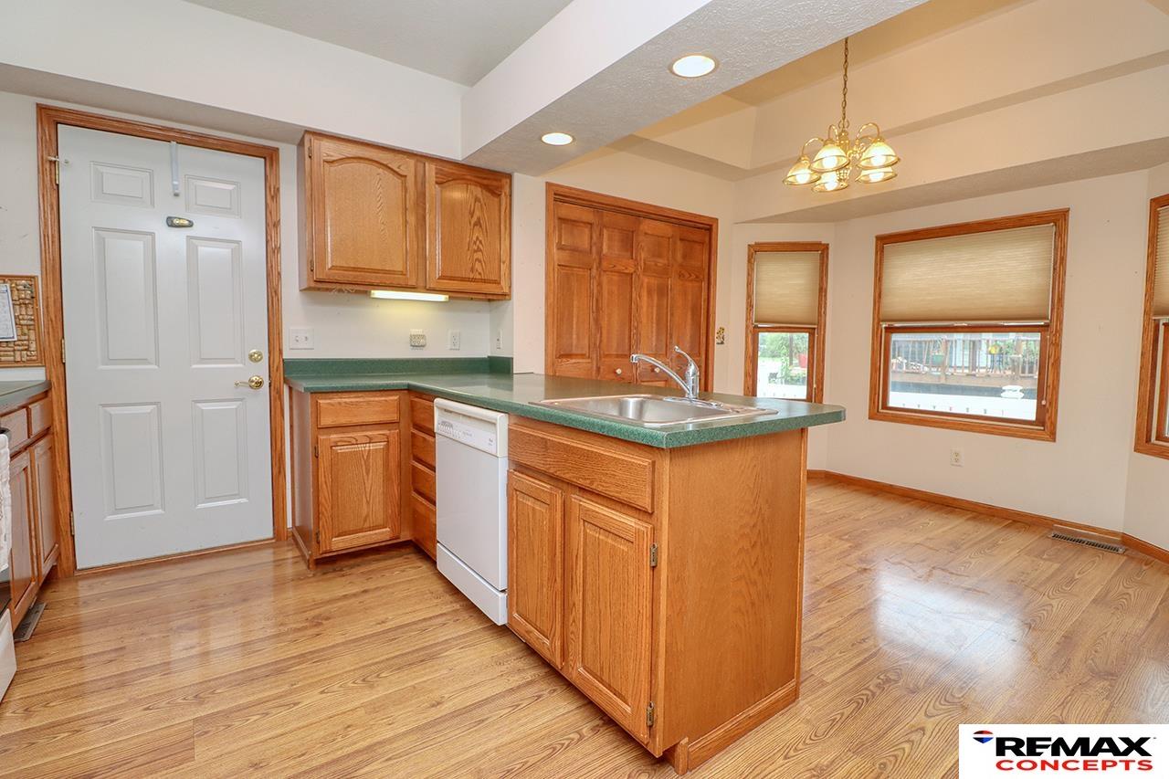 Kitchen with oak cabinetry, a green island countertop and sink, and hardwood flooring.