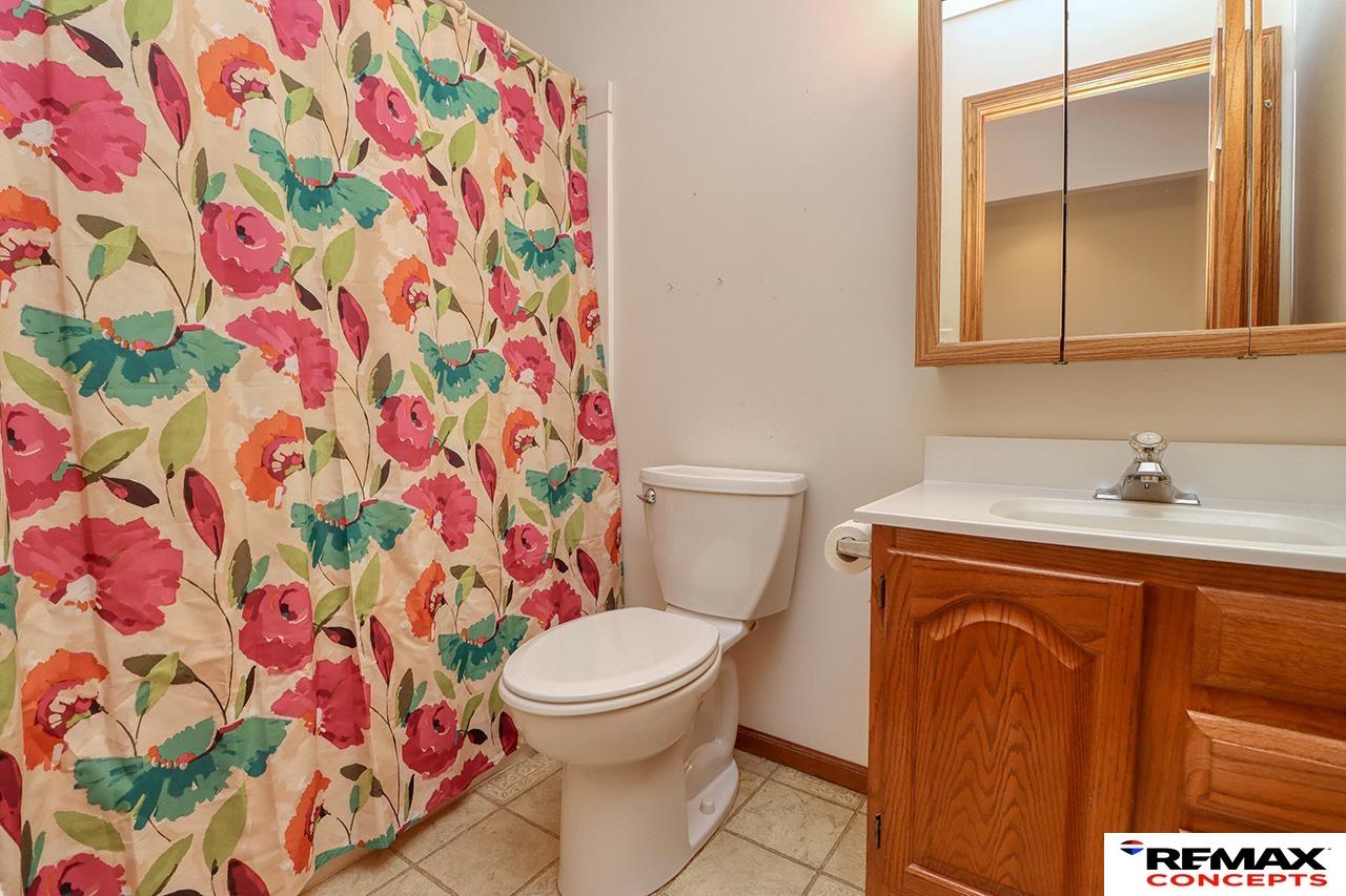 Bathroom with a colorful floral shower curtain and wood vanity.
