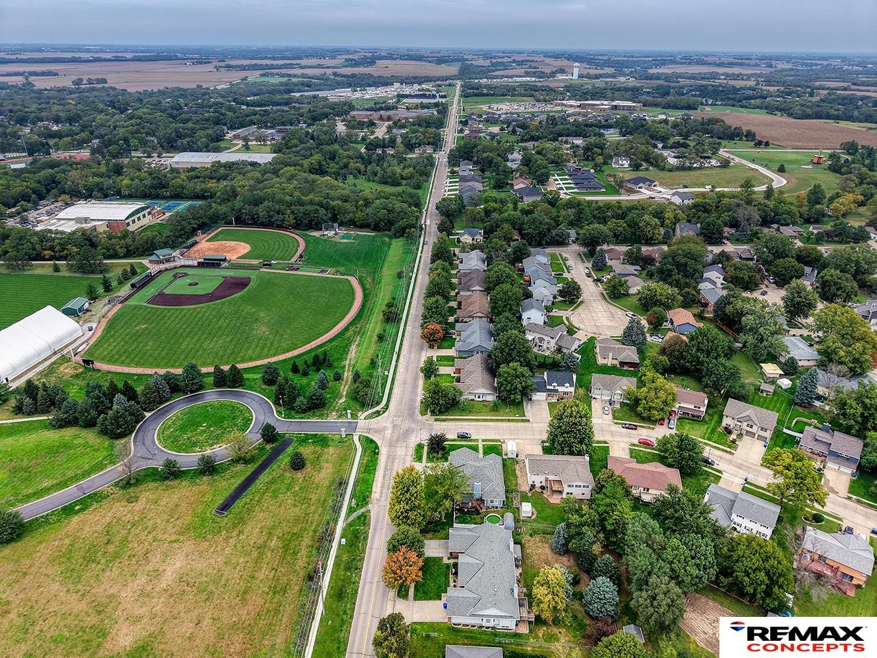 Aerial view of a residential neighborhood beside baseball fields, with farmland stretching to the horizon.