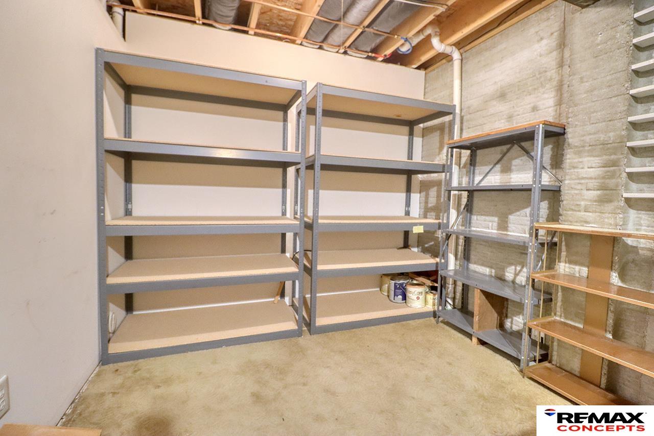 Basement storage room with metal shelving, exposed ceiling joists, and concrete walls.