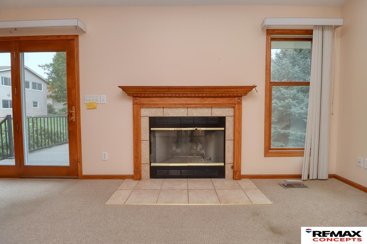 Unfurnished living room with a wood-trimmed fireplace, tiled hearth, and sliding glass doors to a deck.