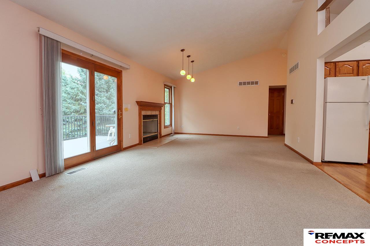 Empty living room with a wood-trimmed fireplace and sliding glass doors opening onto a deck.
