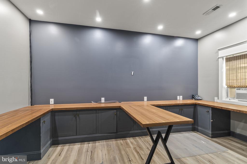 Workspace with wraparound butcher-block counters, dark cabinets, and a gray accent wall.