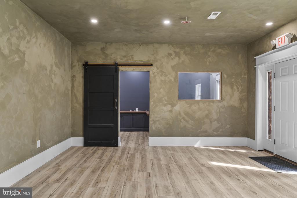 Empty room with mottled walls, light wood-look floors, and a black sliding barn door.