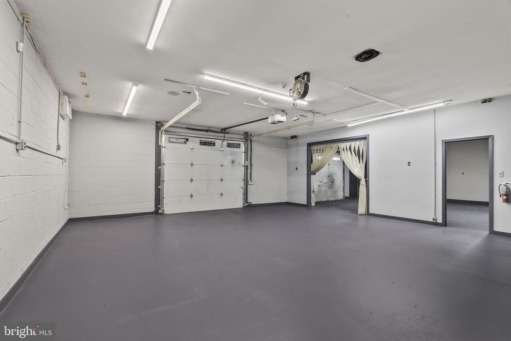 Empty garage with a closed overhead door, gray floor, and adjoining doorways.