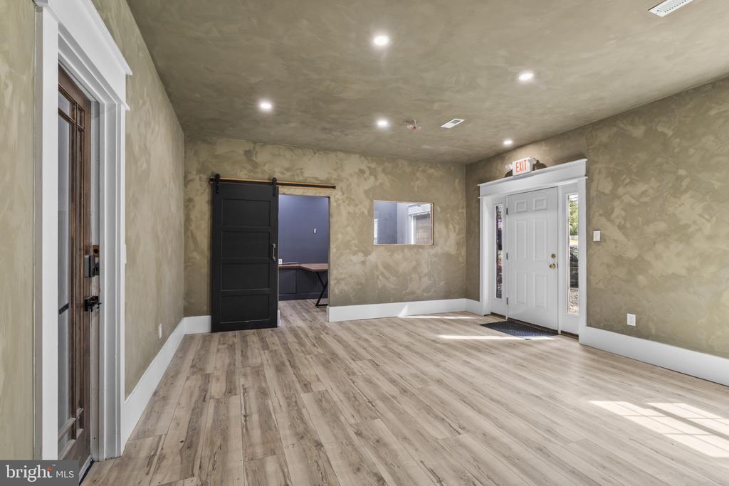Vacant room with light wood-look flooring, mottled walls, and a black sliding barn door.