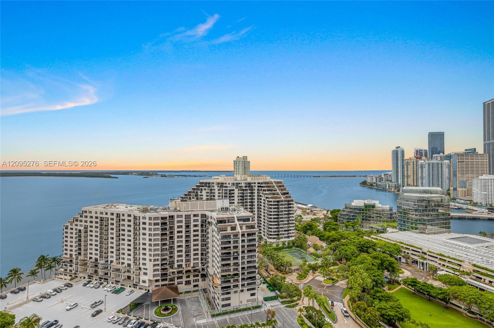 Waterfront condominium towers overlook Biscayne Bay and Miami’s downtown skyline at sunset.