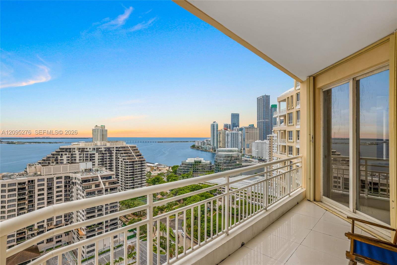 High-rise balcony overlooking Biscayne Bay and the Miami skyline at sunset.