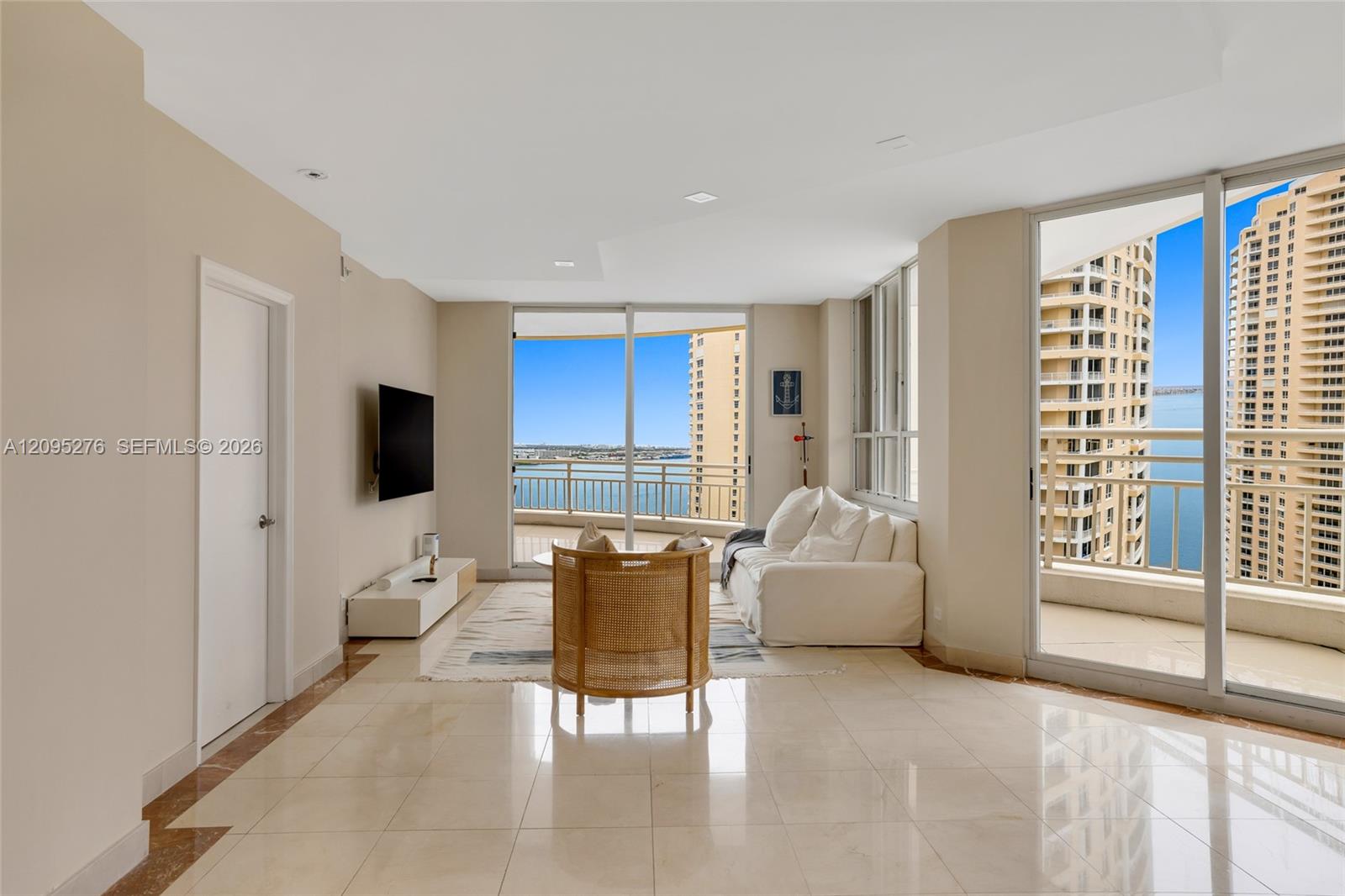 Condo living room with floor-to-ceiling windows, balcony, and water views.