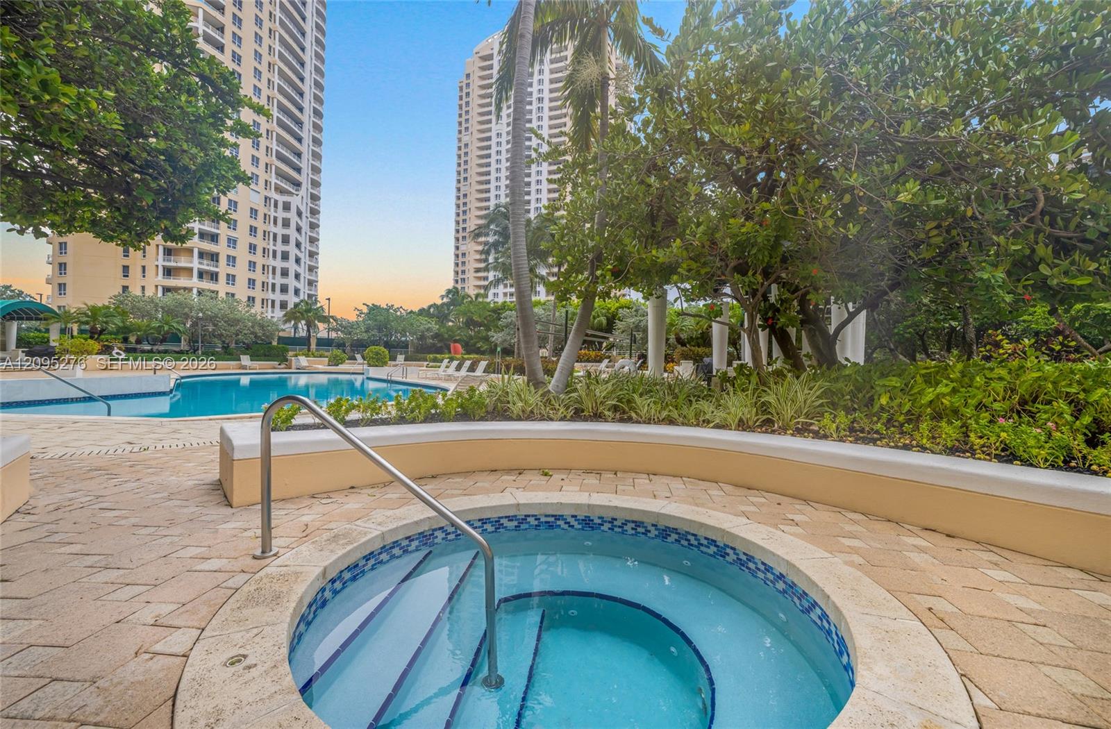 High-rise condominium pool courtyard with a circular spa, palm trees, and landscaped gardens.