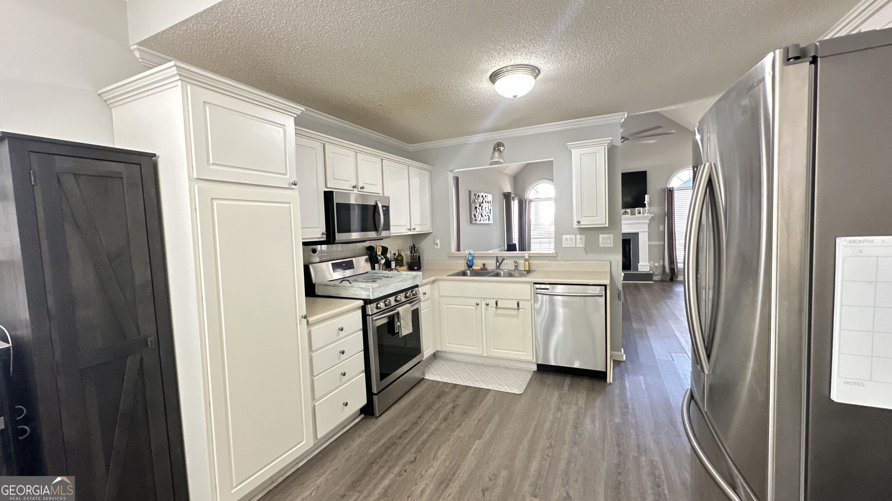 Kitchen with white cabinets, stainless steel appliances, and an opening to the living area.
