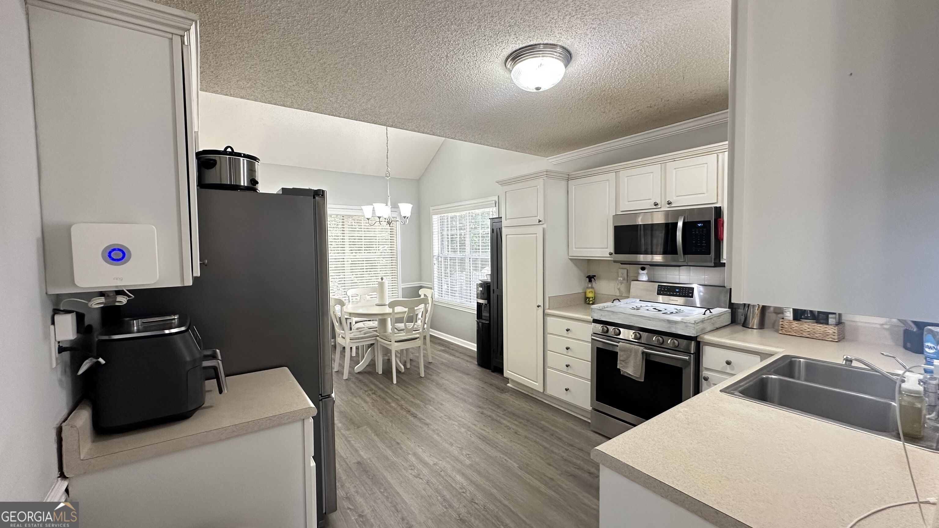 Kitchen with white cabinetry, stainless steel appliances, and a small dining nook by the windows.