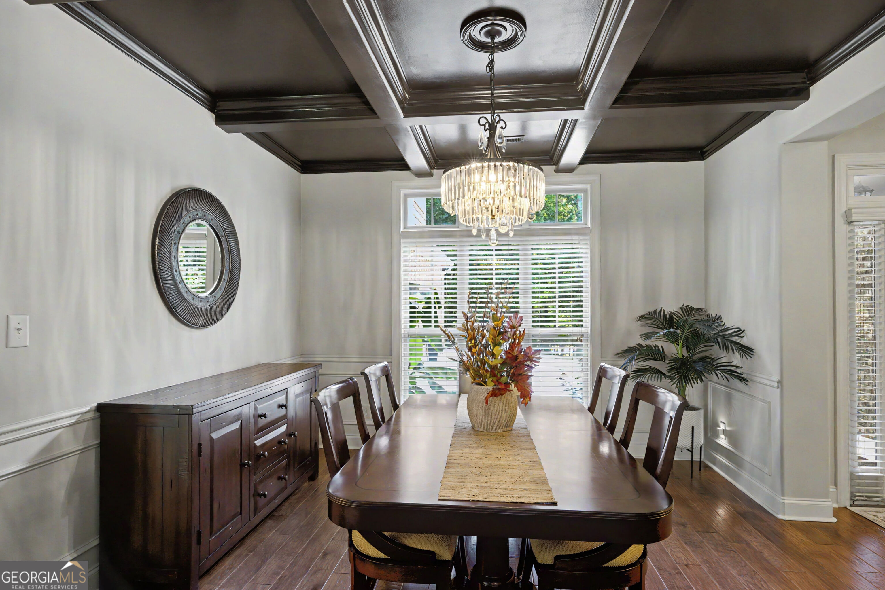 Dining room with a dark wood table, crystal chandelier, and coffered ceiling.